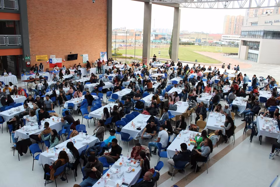 Corporate event in an indoor arena with dozens of long clothed tables and hundreds of attendees