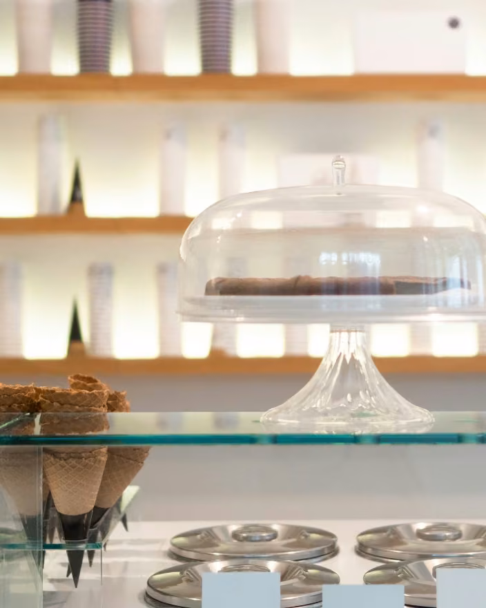 Vitrina de heladería con conos de barquillo, una campana de vidrio y bandejas de acero, en la feria Cafés de Colombia Expo