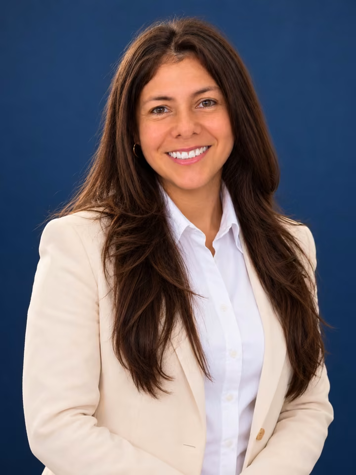 Katerine Guarín, Medipro's sales director, smiling in a beige blazer against a blue background
