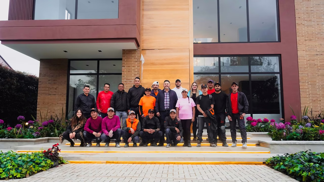 Equipo de Smartinn posando en las escaleras de entrada de una casa terminada de ladrillo y madera