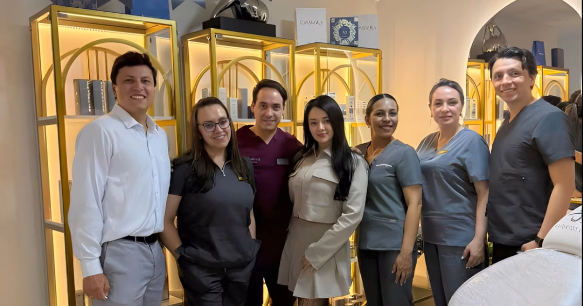 Equipo de ocho personas de SR Expertos en Piel, la mayoría con uniforme gris, posa frente a estanterías doradas con productos en la clínica